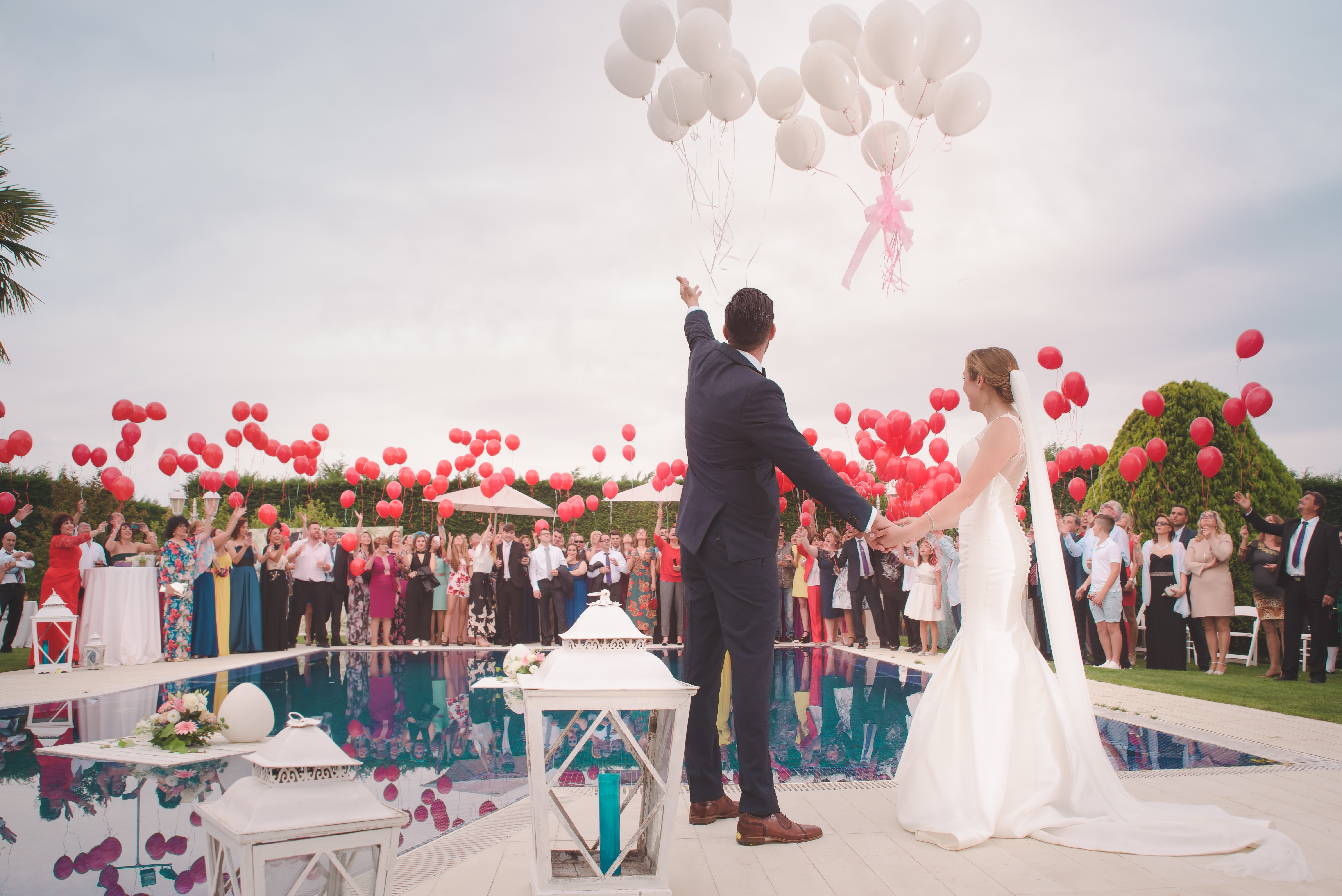wedding guests with red balloons and the bride and groom