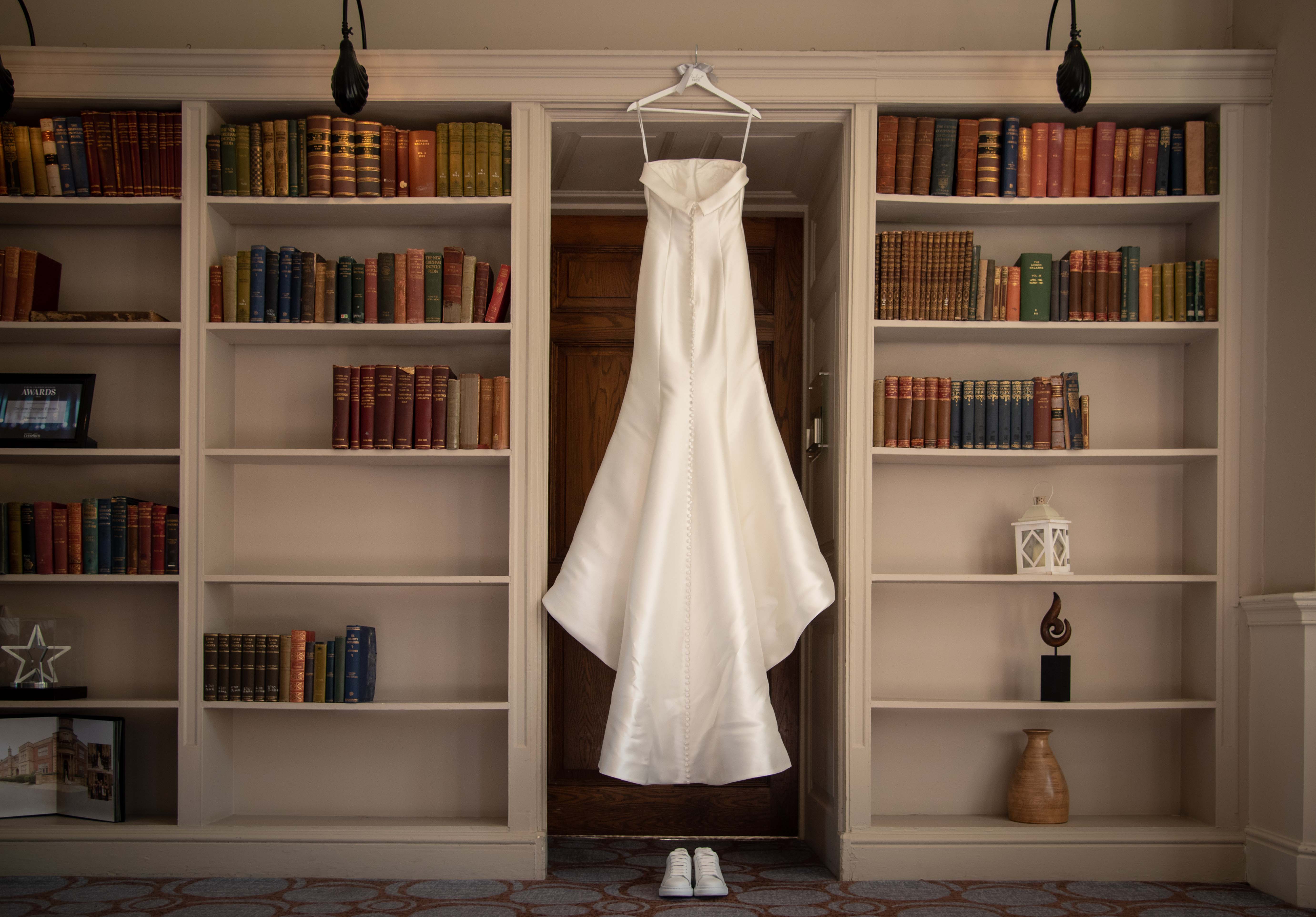 Satin wedding dress hung up on a doorframe