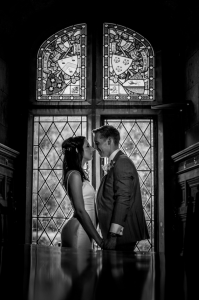 Bride and groom in front of a stained glass window at Tower wedding venue