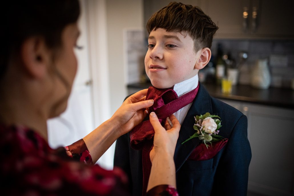 Bride doing up her son's cravat on the wedding day