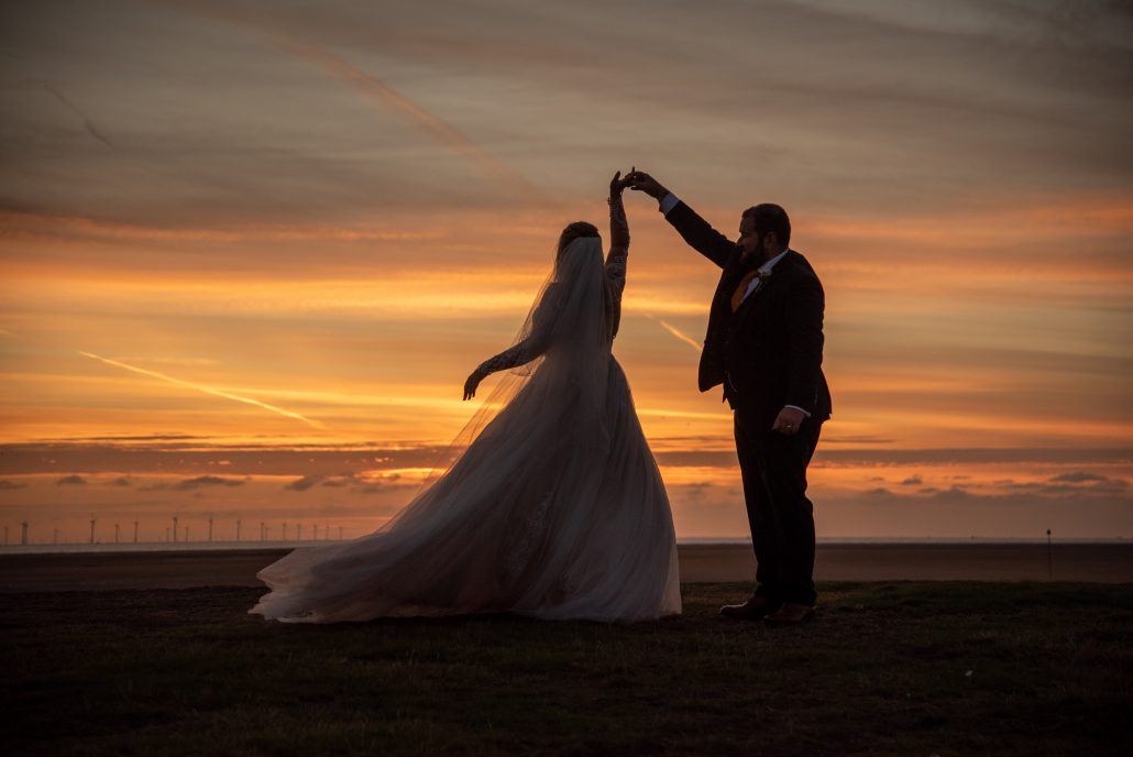 Couple dancing on the beach at sunset on their wedding day