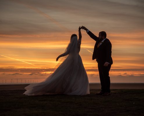 Couple dancing on the beach at sunset on their wedding day